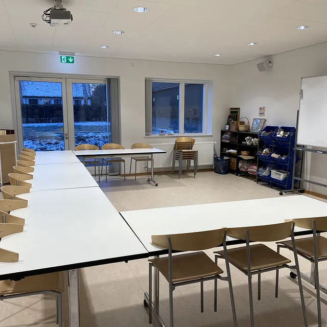 Mødelokale med U-formet bordopstilling og en whiteboardtavle.