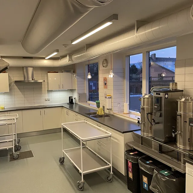 Moderne kirkekøkken med udstyr i rustfrit stål og rulleborde.