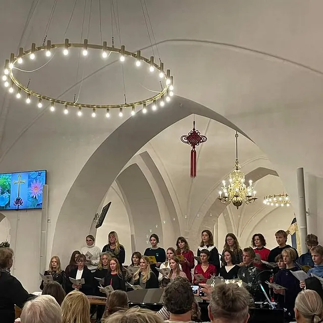 Ungdomskor synger under en stor moderne lysekrone i kirken.