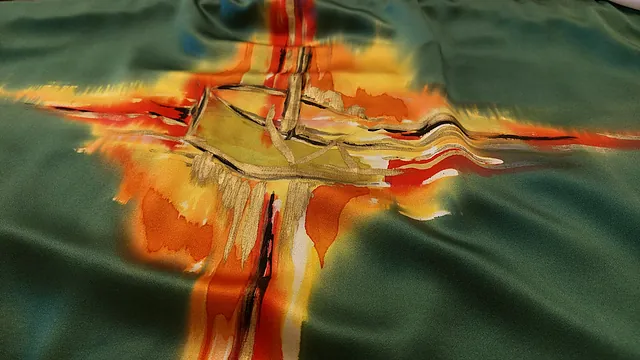 Nærbillede af grønt liturgisk stof med malet kors og skib.