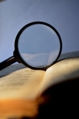 Et forstørrelsesglas, der ligger på en åben bog eller bibel.